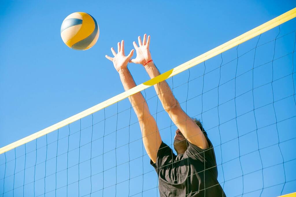 Beach volleyball player blocking the ball at the net